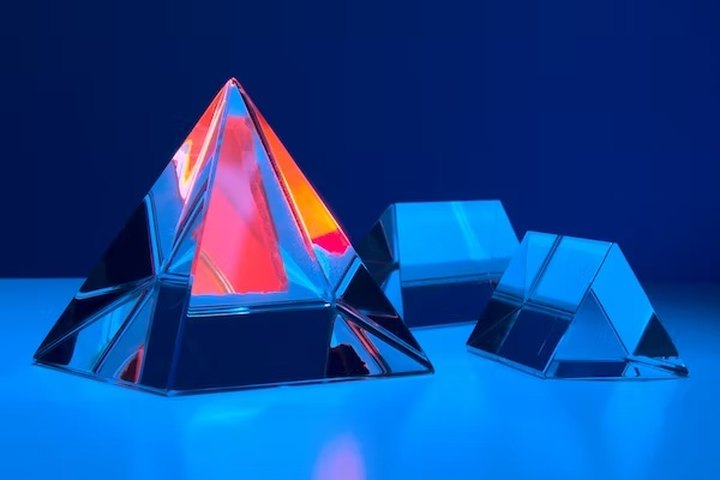 Optical glass prisms under blue light, representative of precision optical components cleaned by Unitech Shyre systems