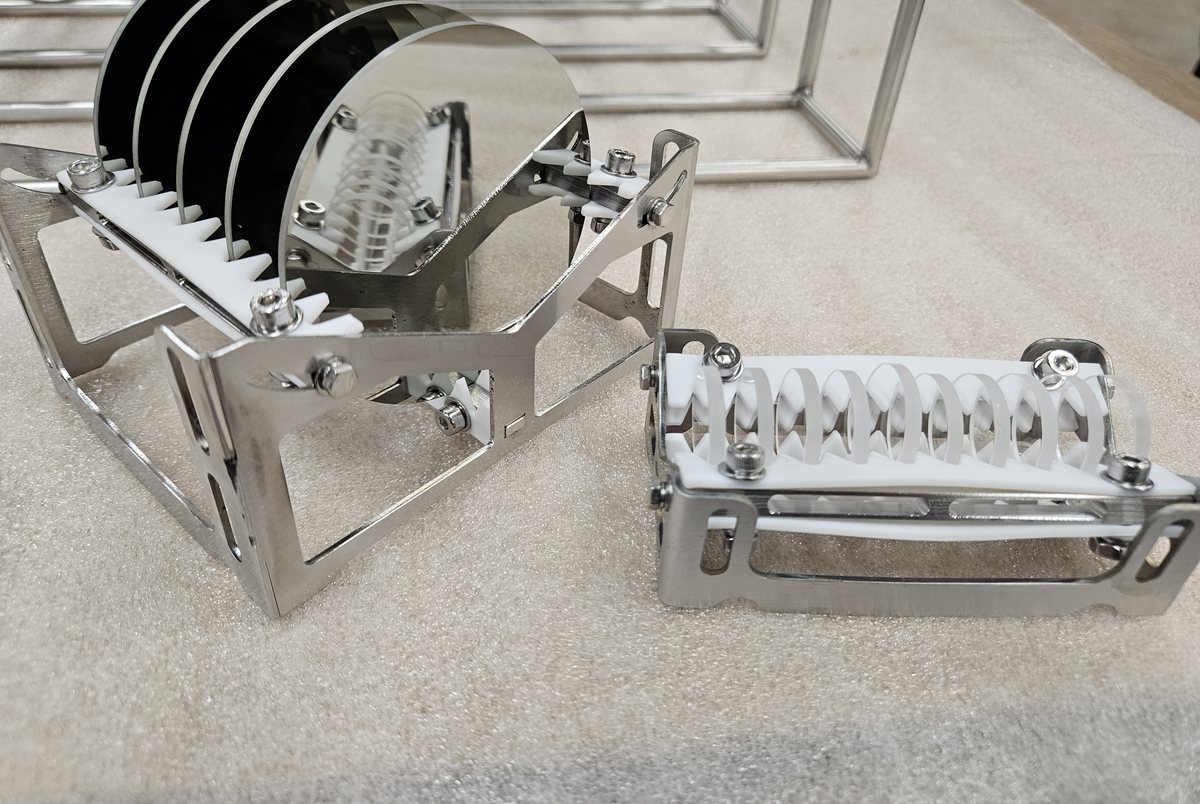 Stainless steel precision cleaning carriers with PTFE location combs, one loaded with optical discs, beside welded stainless basket frames